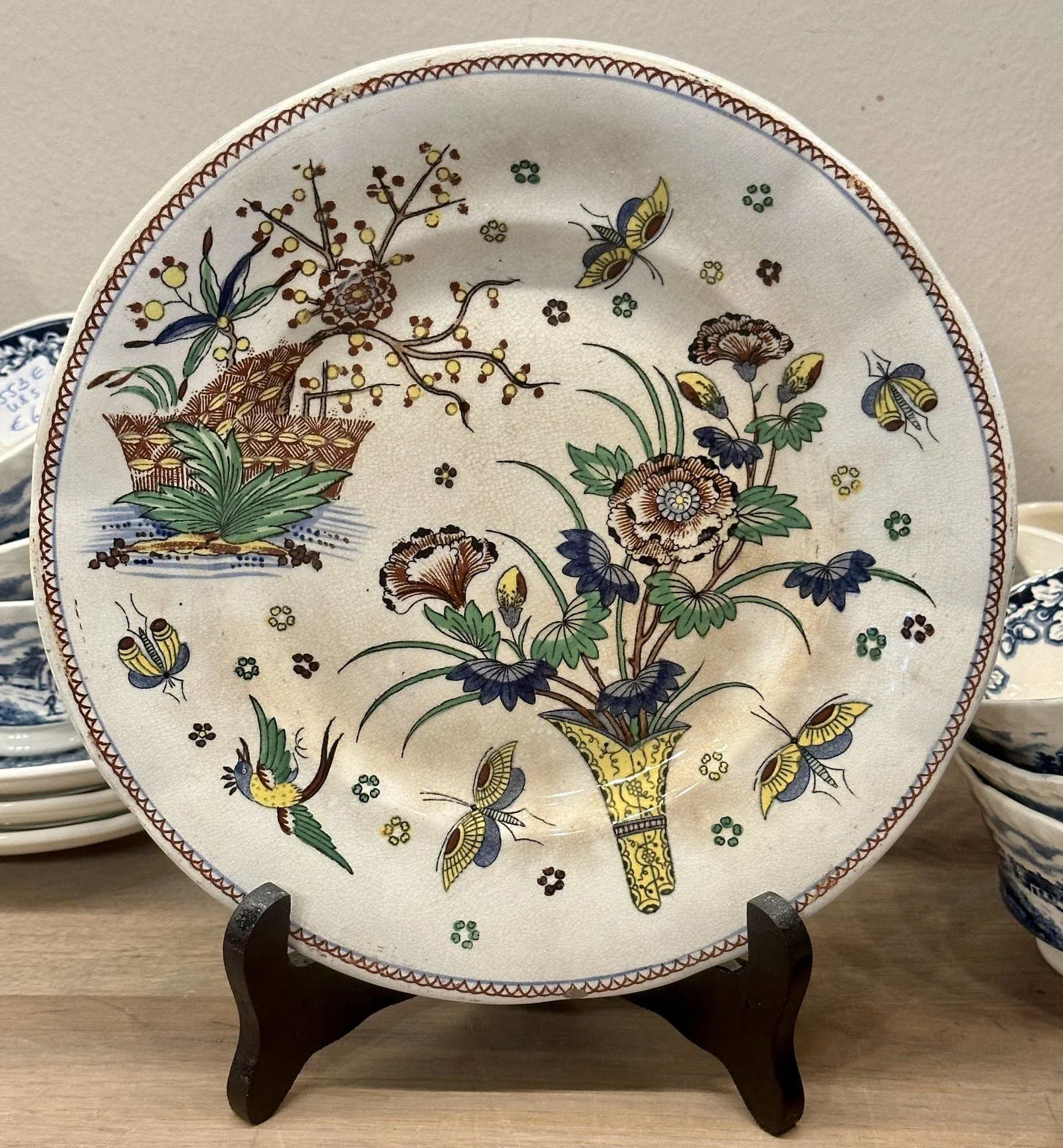 Bord / Sierbord – Boch Frères – décor met een bloemenvaas, vogel en vlinders in geel/groen/blauw Bord / Sierbord – Boch Frères – décor met een bloemenvaas, vogel en vlinders in geel/groen/blauw