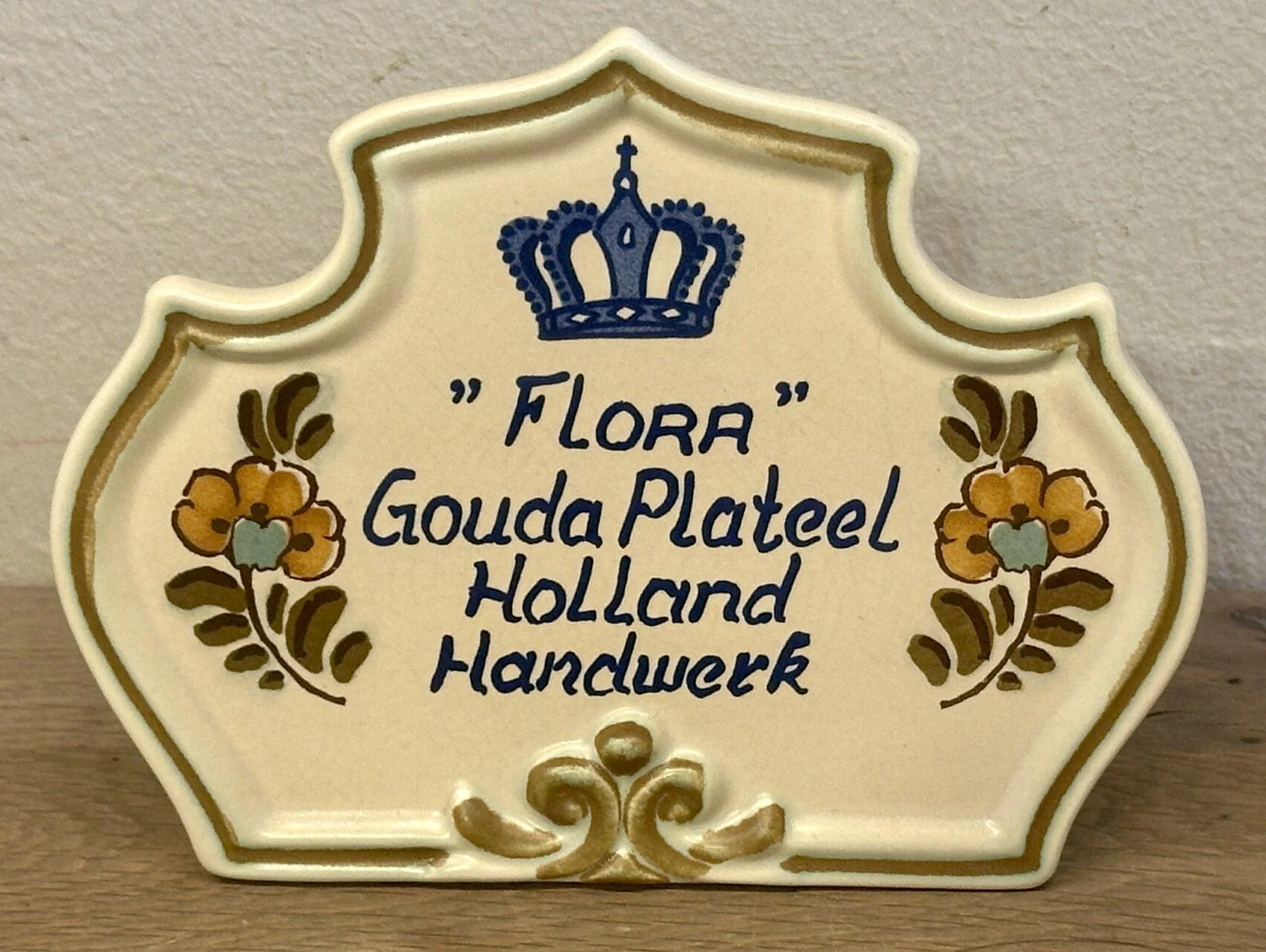 Winkelreclame / Winkeldisplay voor “FLORA” GOUDA PLATEEL HOLLAND HANDWERK – lichtbruine ondergrond
