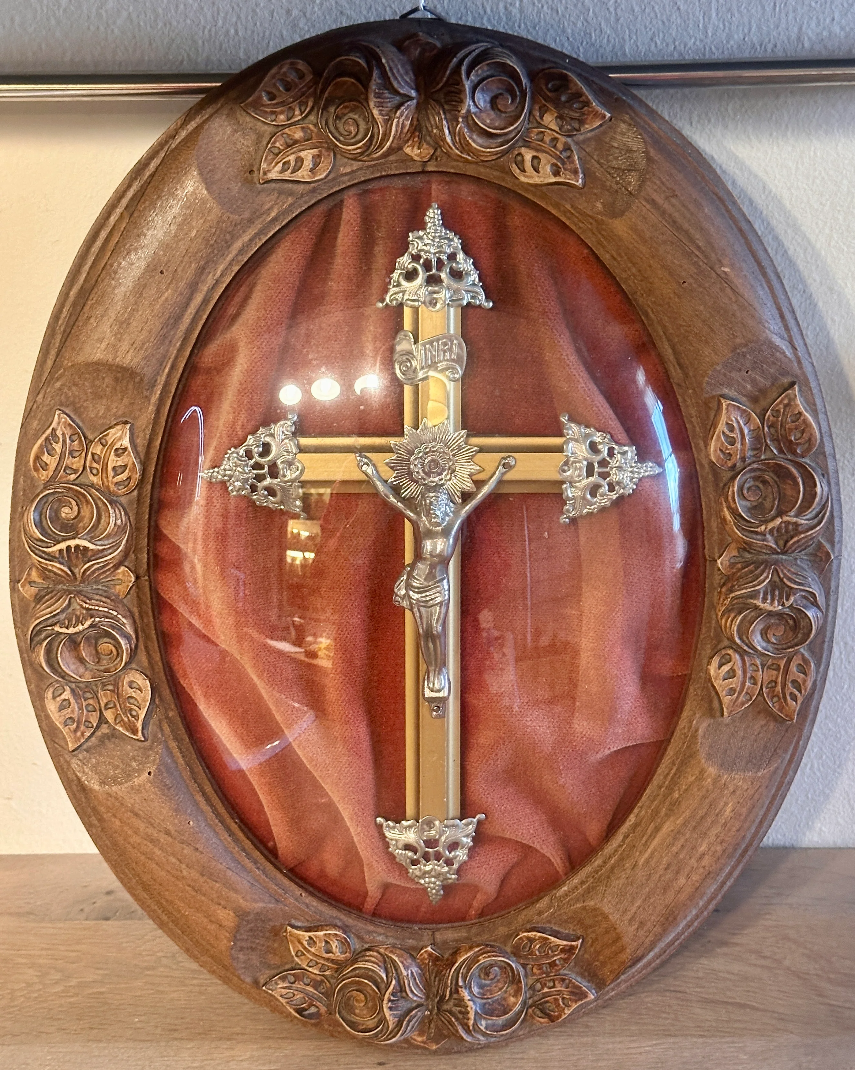 Zogenaamde ‘Bolle Jezus’ – ingekaderd kruisbeeld onder bol/gebombeerd glas – ovaal houten lijst – gevat in een fluwelen roze ondergrond